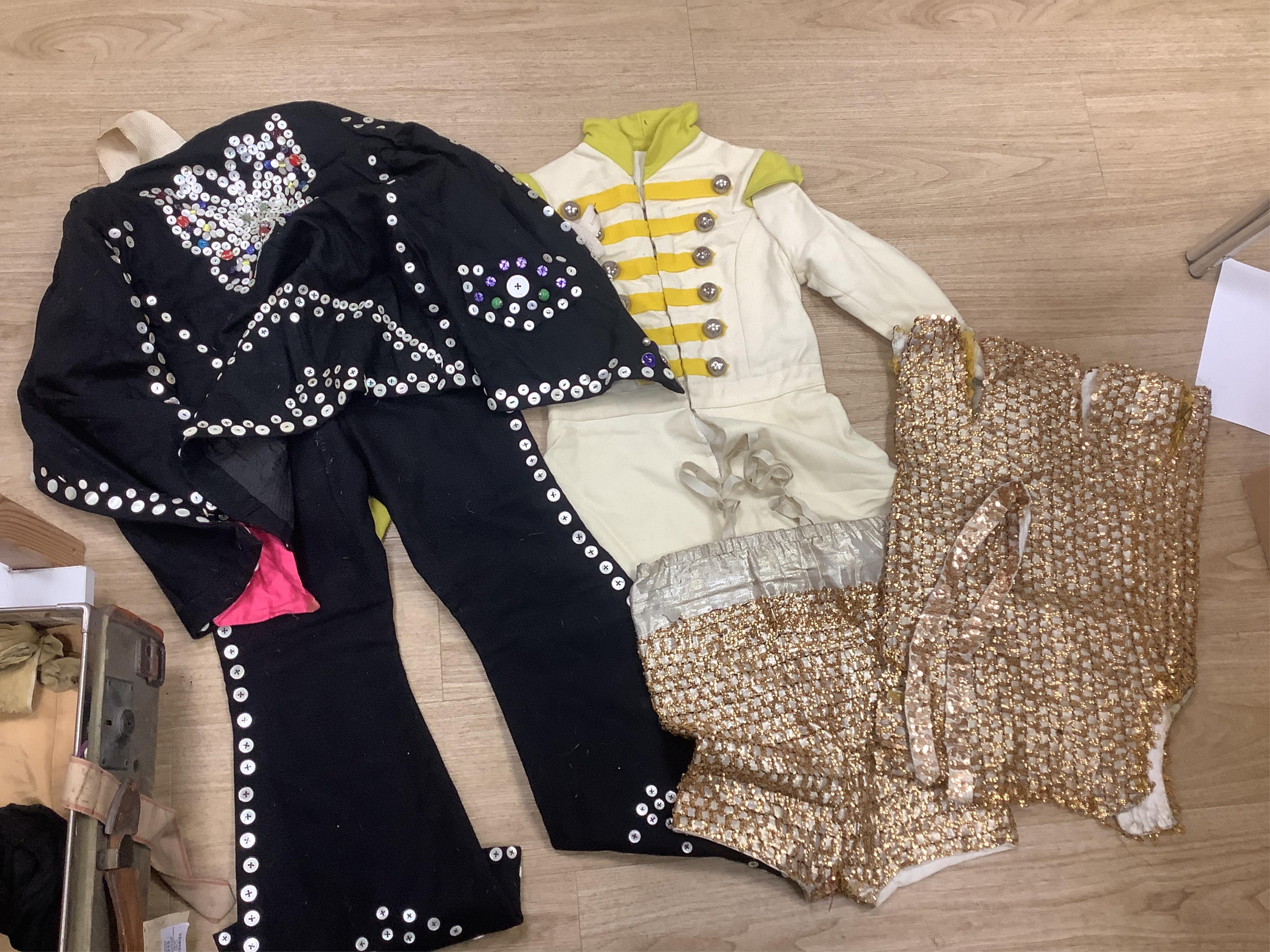 Two trunks containing a collection of children’s fancy dress from early 20th century, including an unusual child’s ‘pearly king’ suit, two earlier stockinette hats, a length of long silver metal fringing, ribboning etc.,